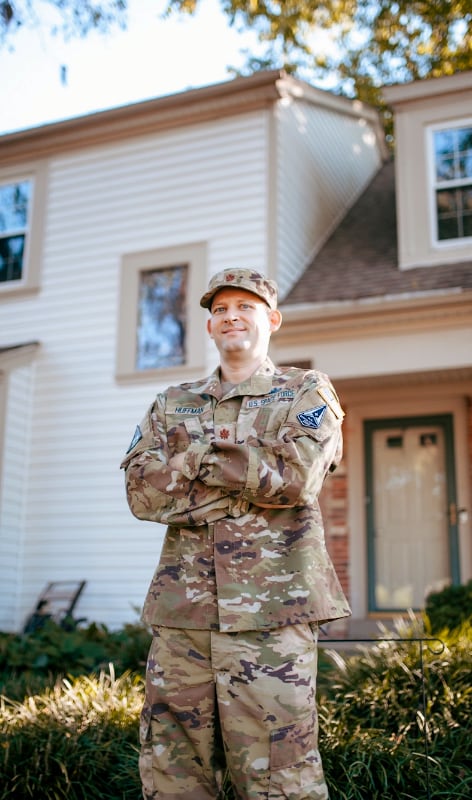 Man in camo standing in front of house