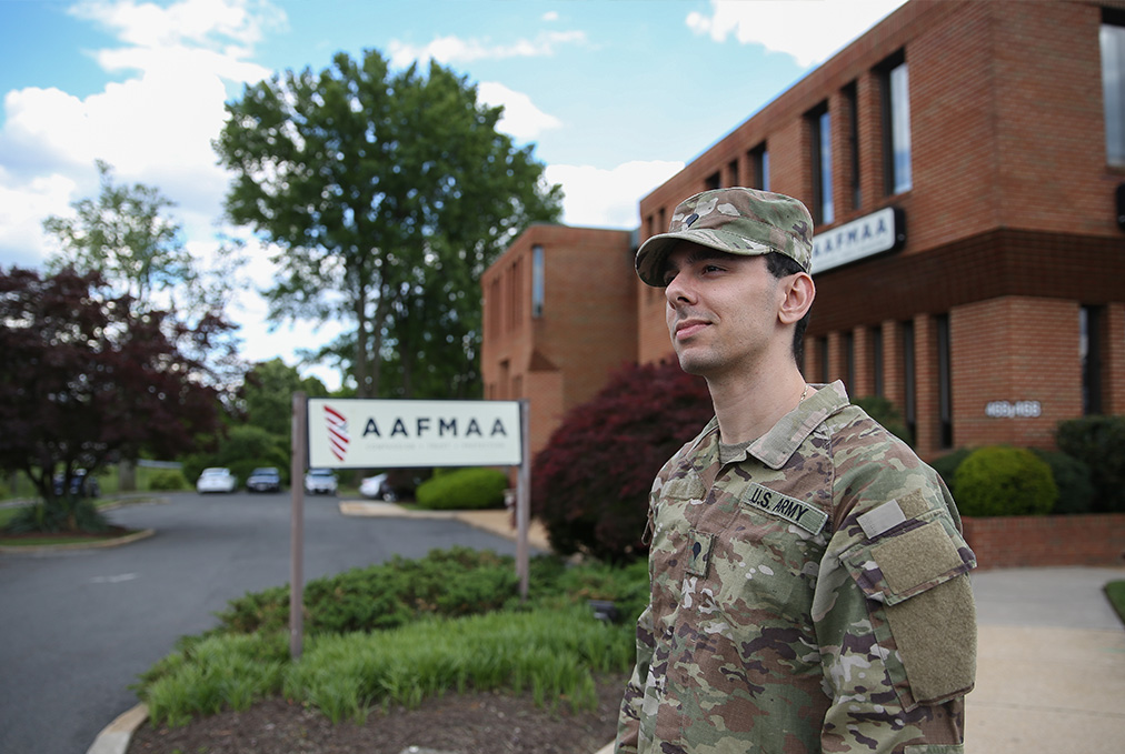 Man in camo standing in front of house