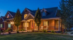 A brick home in the evening with warm lights on inside.