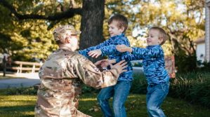 A father in his military uniform hugging his two sons.