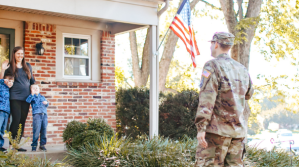 A family is waving to their father who's dressed in an American military uniform.